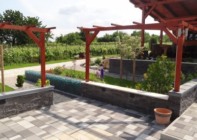 Lábazati kővel burkolt támfal és kombi térkővel burkolt felület a Flamingó Panzió parkjában.