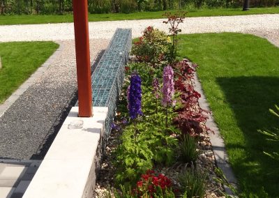 Évelőágyás, mellette üvegsziklával feltöltött gabion támfal az Etyeki Flamingó Panzió kertjében.