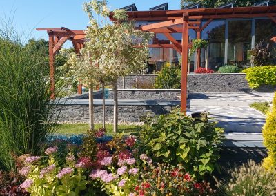 Flamingó Panzió parkja Etyeken - Kacskaringós támfalak a burkolat szélén lugasok és futószőlő.